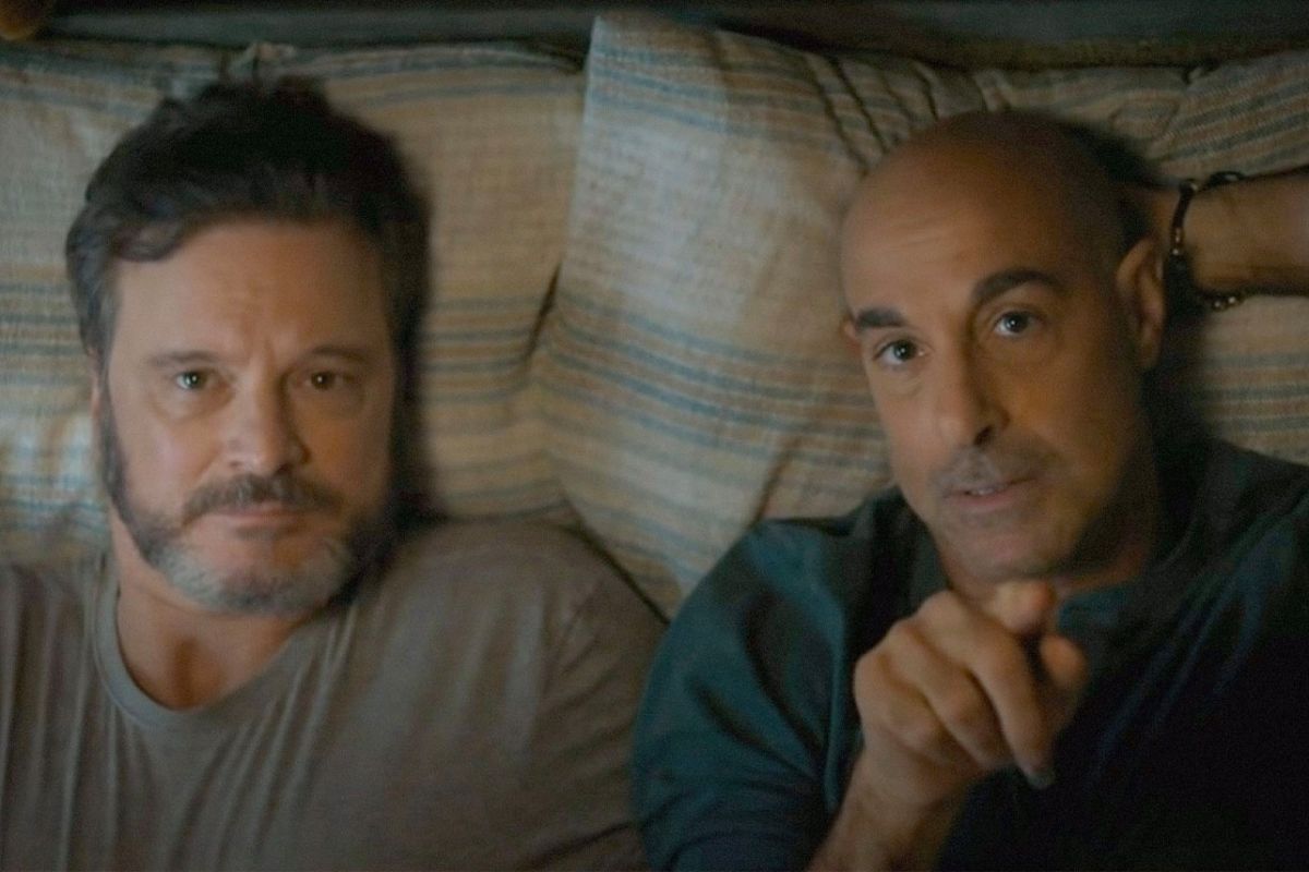 Colin Firth och Stanley Tucci ligger bredvid varandra i en säng och pekar mot en karta med stjärnor.