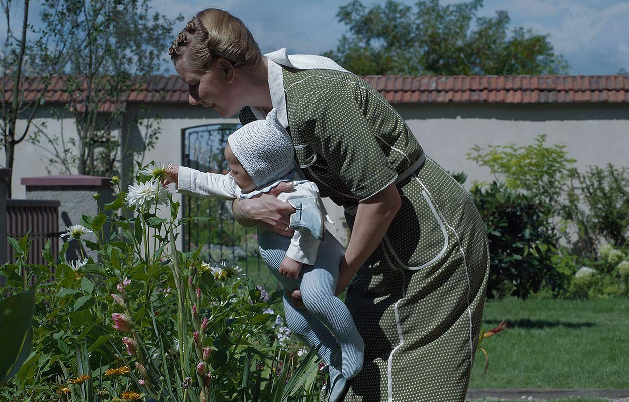 "Auschwitz drottning" håller upp ett litet barn och låter det lukta på blommorna.