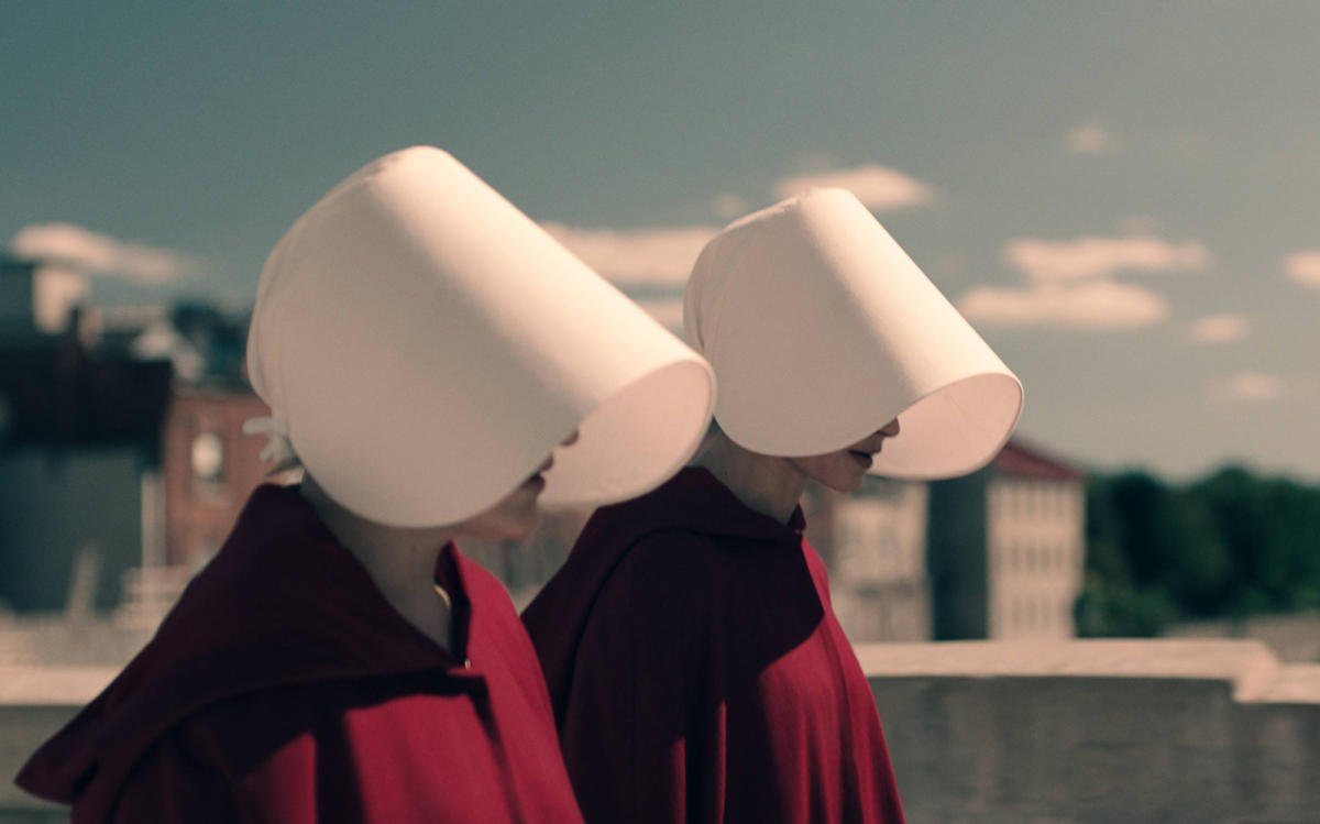 Två kvinnor går bredvid varandra i sci-fi serien The Handmaid's Tale.