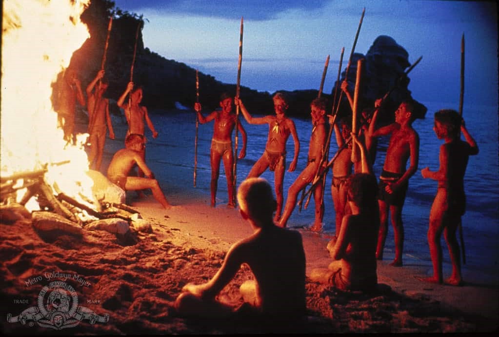 Pojkarna i Flugornas herre dansar runt lägerelden på en strand.