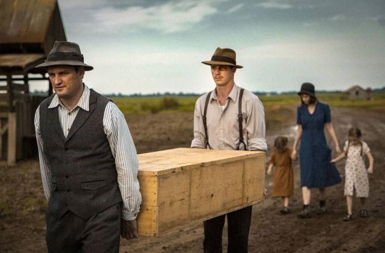 Skådespelarna i Mudbound bär på en träkista.