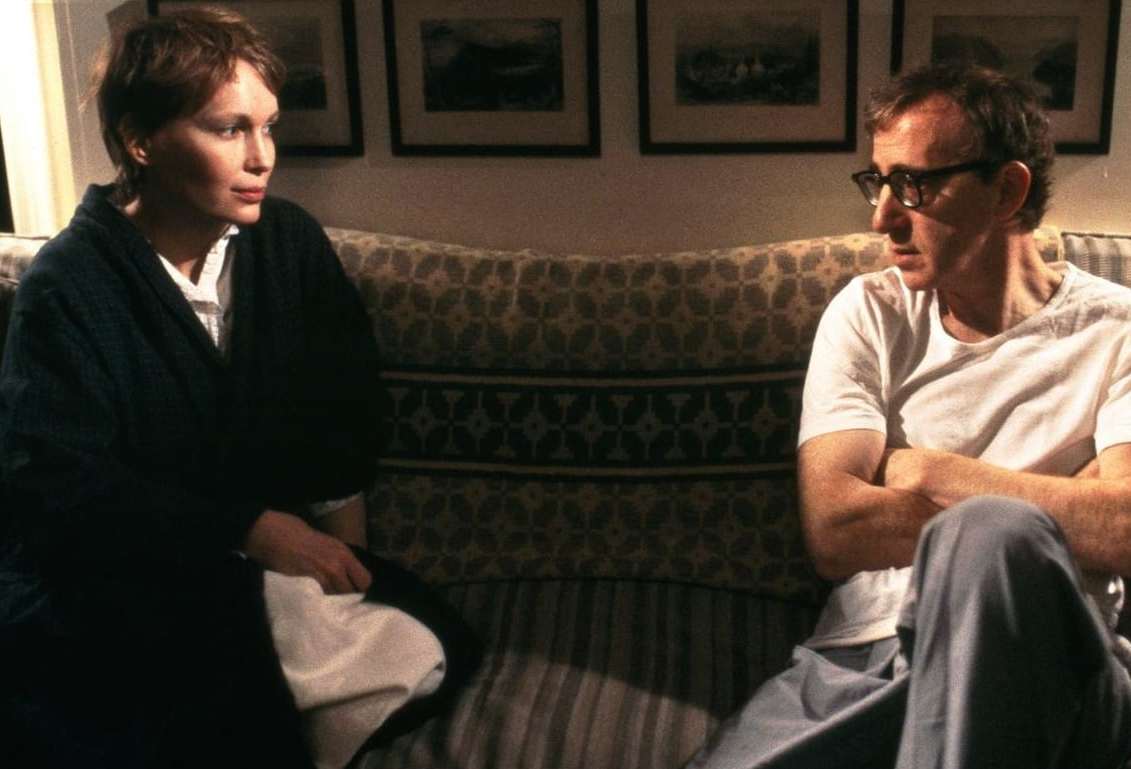 Mia Farrow och Woody Allen sitter längst ifrån varandra i en soffa och tittar på varandra.