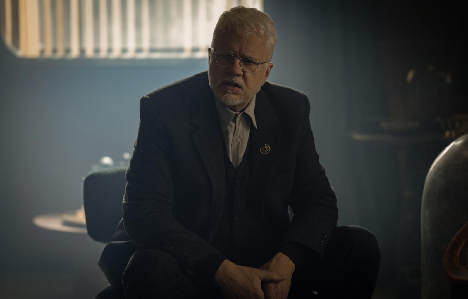 Tim Robbins som borgmästaren i "Silo". Han sitter på en stol och ser bekymrad ut.