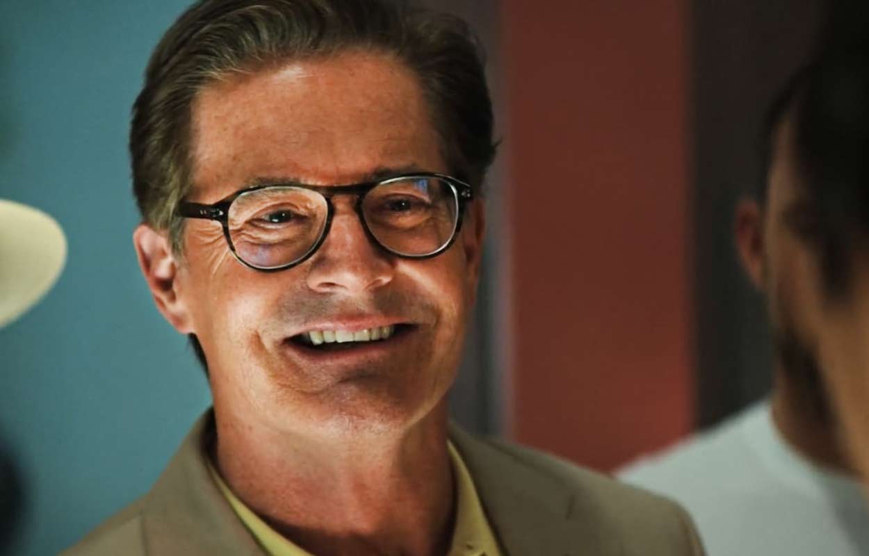 Kyle MacLachlan står och ler.